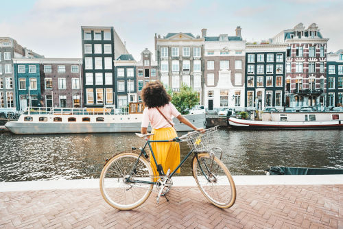 Une touriste regardant des maisons à Amsterdam contre son vélo